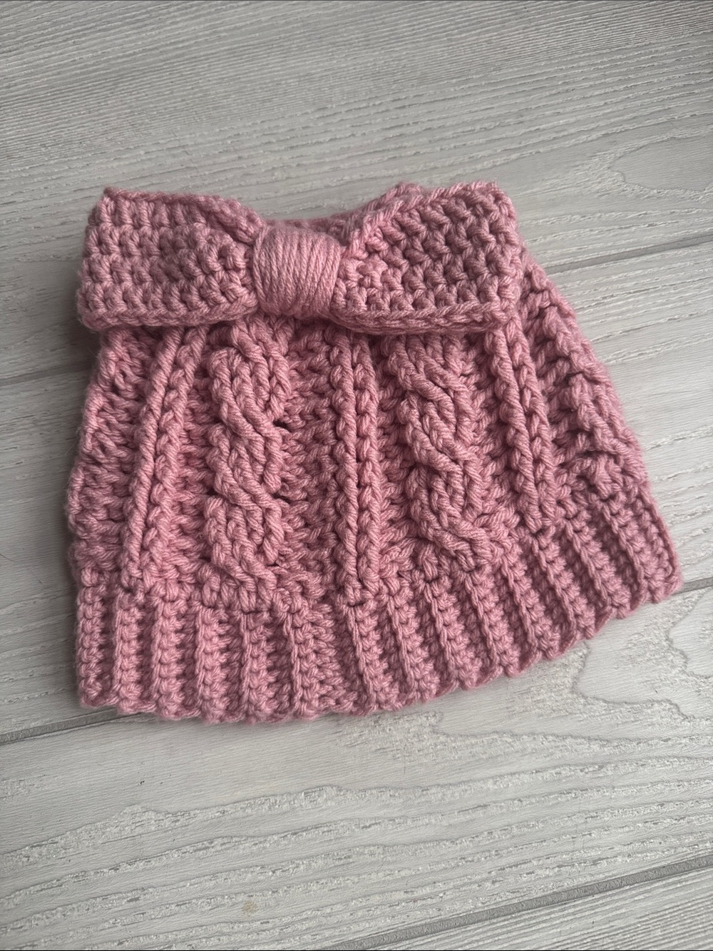 Pink Knit Beanie features a cable-knit design and a bow accent with open top